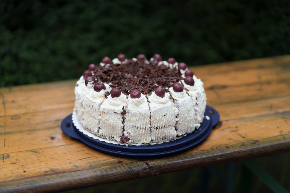 Eine Schwarzwälder Kirschtorte auf einer blauen Kuchenteller und einem Holztisch.